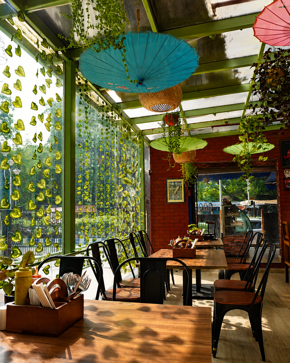 Good Food Café interior with colourful hanging umbrellas, wooden tables and lush greenery